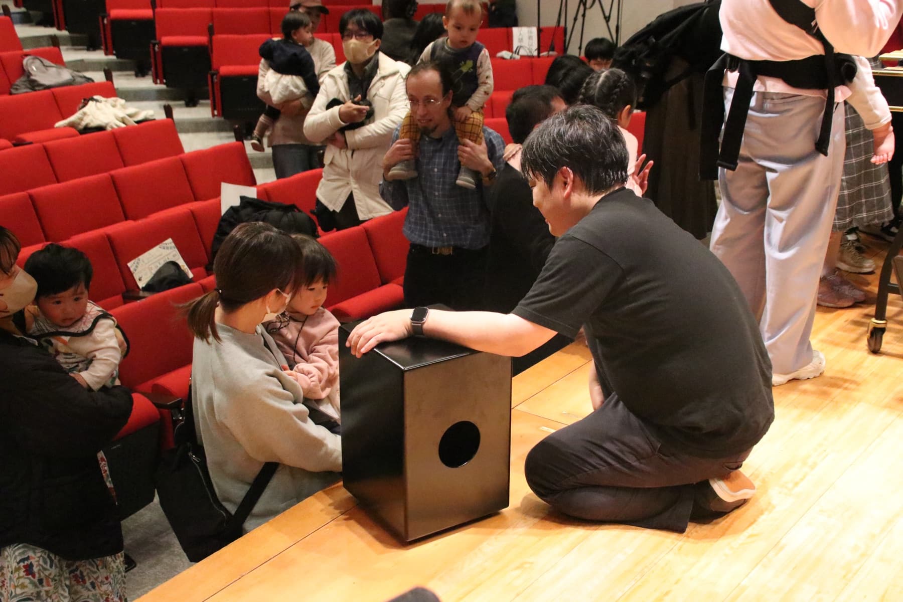 指揮棒を握って演奏家をリードする子どもと、それを見守る奏者たち（指揮者体験の様子・イメージ）